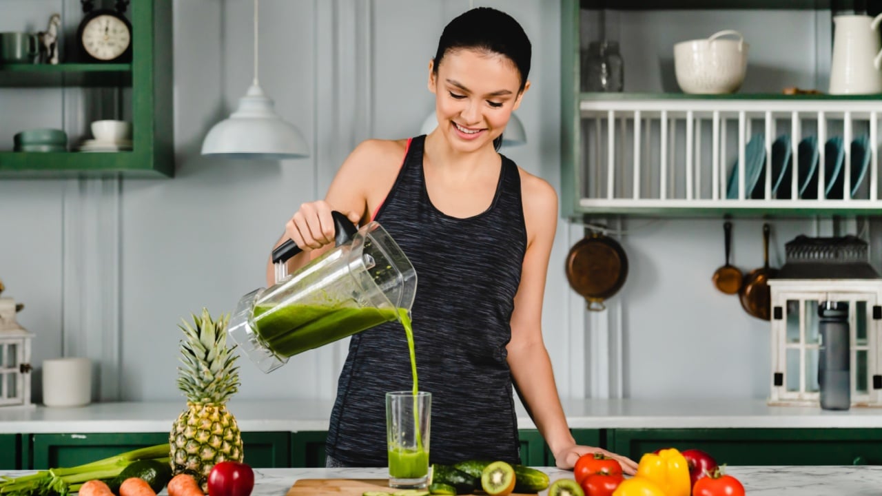 Healthy young woman drinking fresh detox juice in the kitchen. Organic smoothie super food cocktail for losing weight, zero calories, keeping fit posture and body