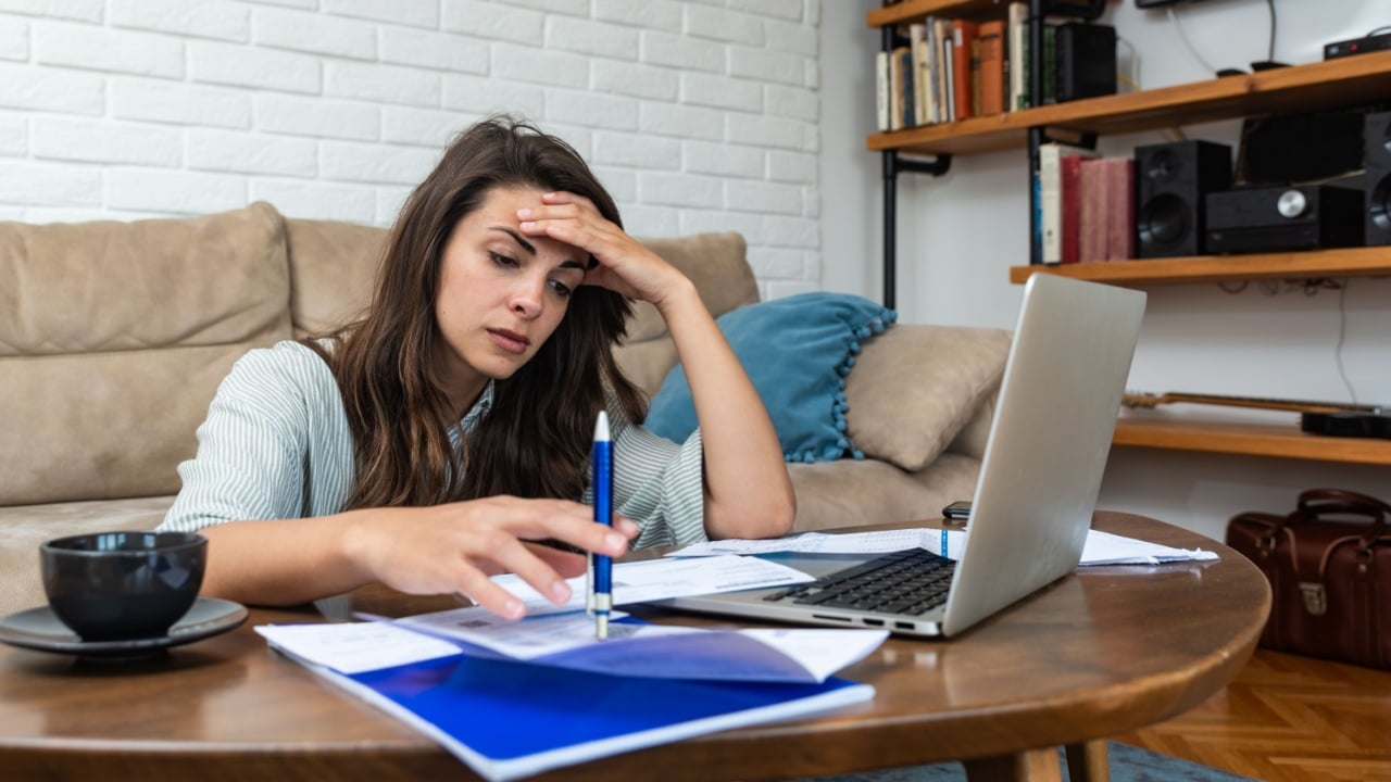 Young stressed woman having issue with utility bills expense, sitting at home trying to calculate and see bad finance bank report, searching for mistake. College student girl with money problem.