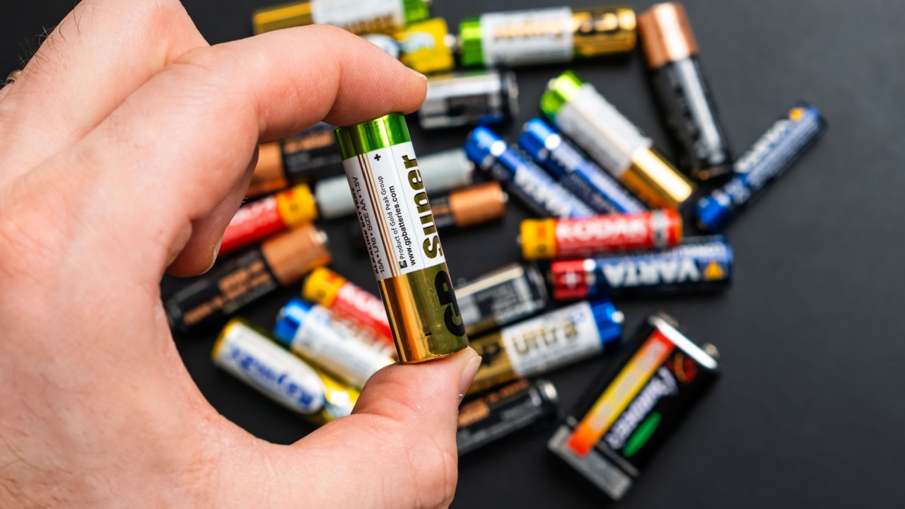BERLIN , GERMANY - APRIL 14 2024: Used alkaline AA batteries in mans hand and on the black table.