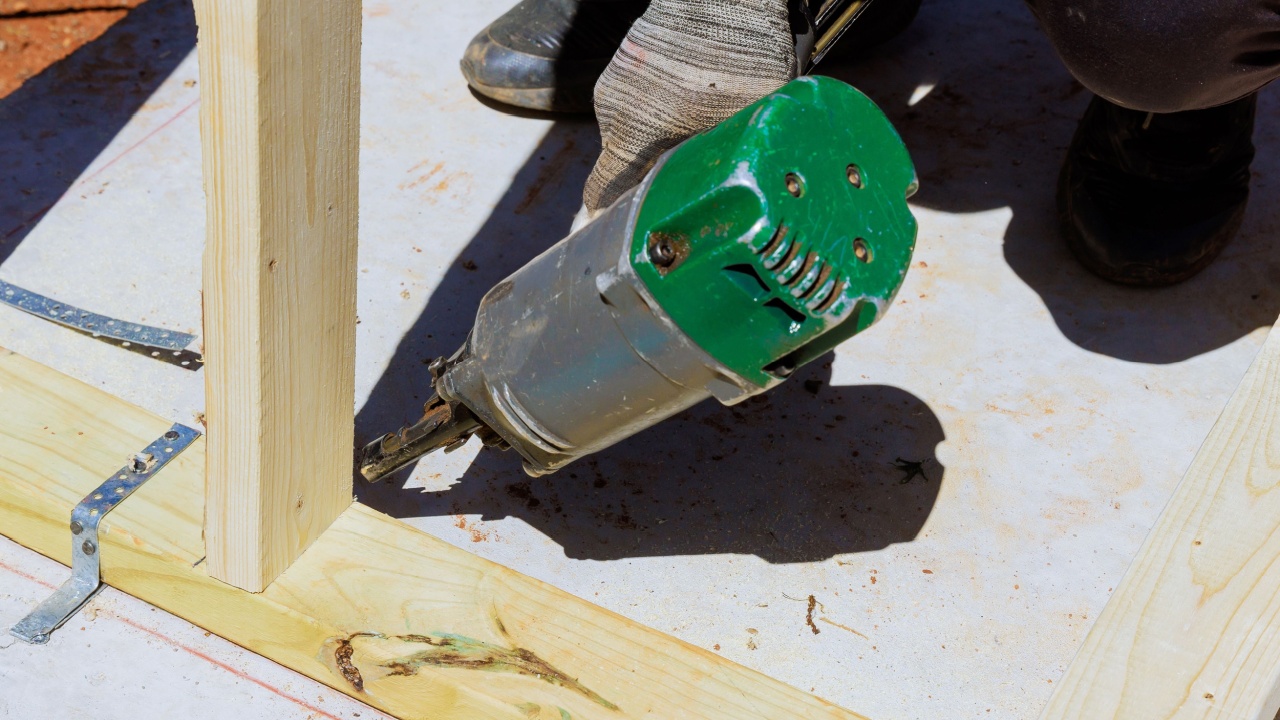 Framer worker installing beams using air nails hammer in nailing wooden frame
