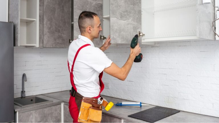 Workers installing new stylish furniture in kitchen