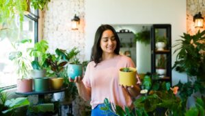 Beautiful hispanic woman holding two different succulents while shopping at a plant shop and making up her mind