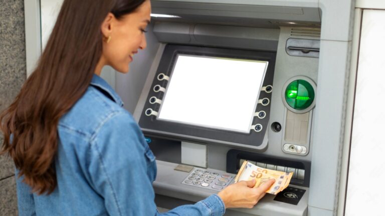 Woman withdrawing Euro cash at ATM machine outside, lady bank client taking banknotes, making financial transactions