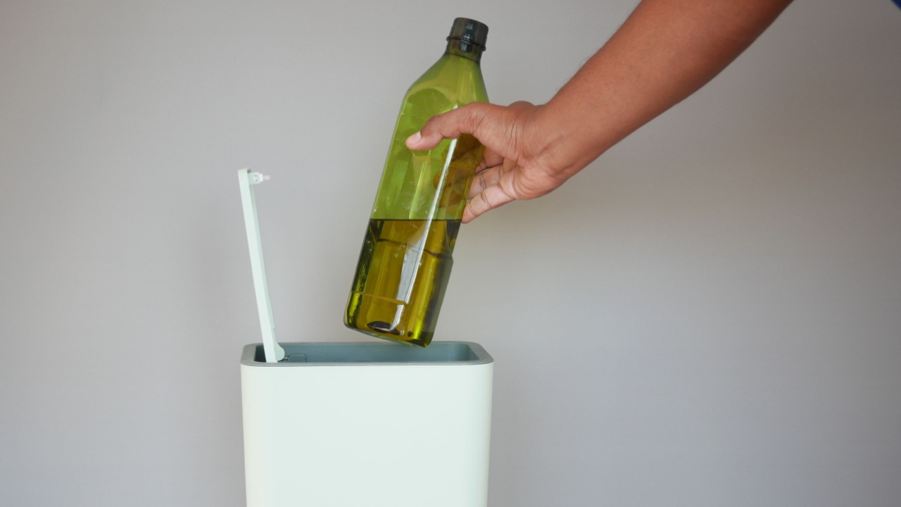throwing cooking oil bottle in a garbage bin
