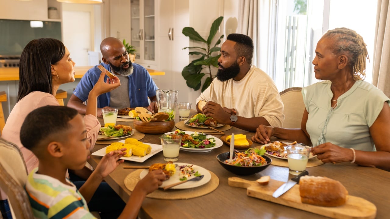 multigenerational family enjoying meal together, sitting around dining table, sharing stories. togetherness, bonding, storytelling, conversation, home, happiness