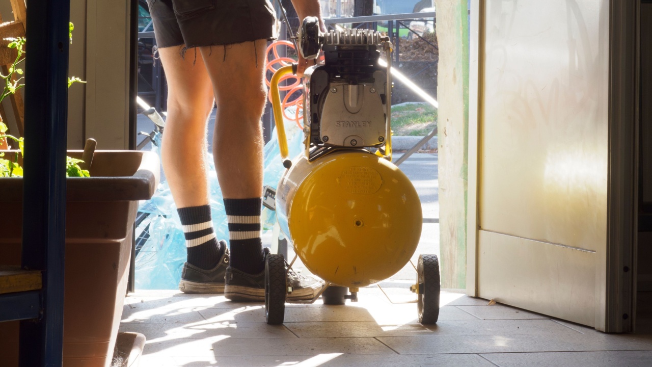 Cremona, Italy - september 19th 2023 Man in a blue shirt is holding a yellow air compressor. The image has a casual and relaxed mood, as the man is standing outside.