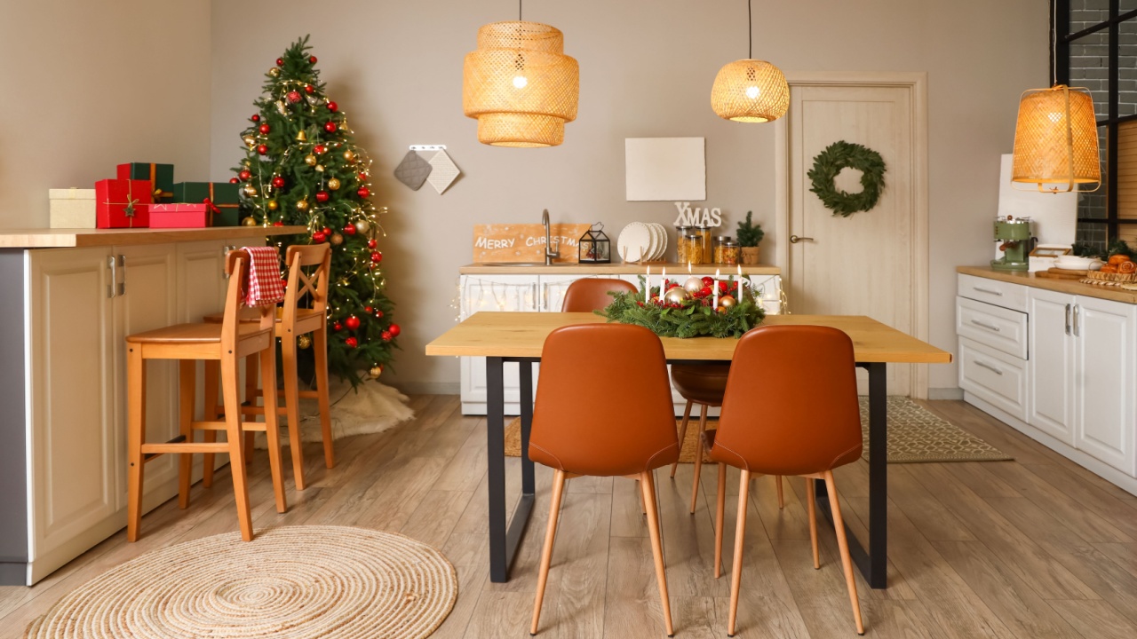 Interior of modern kitchen with glowing lamps, dining table and Christmas tree