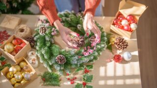 Woman making mistletoe wreath Christmas wreath decoration with hand made DIY winter greenery florist hands making Christmas wreath beautiful mistletoe