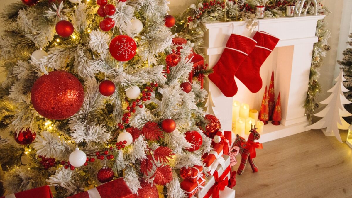 A cozy living room featuring a frosted Christmas tree, stockings by the fireplace, and festive decorations in red and white