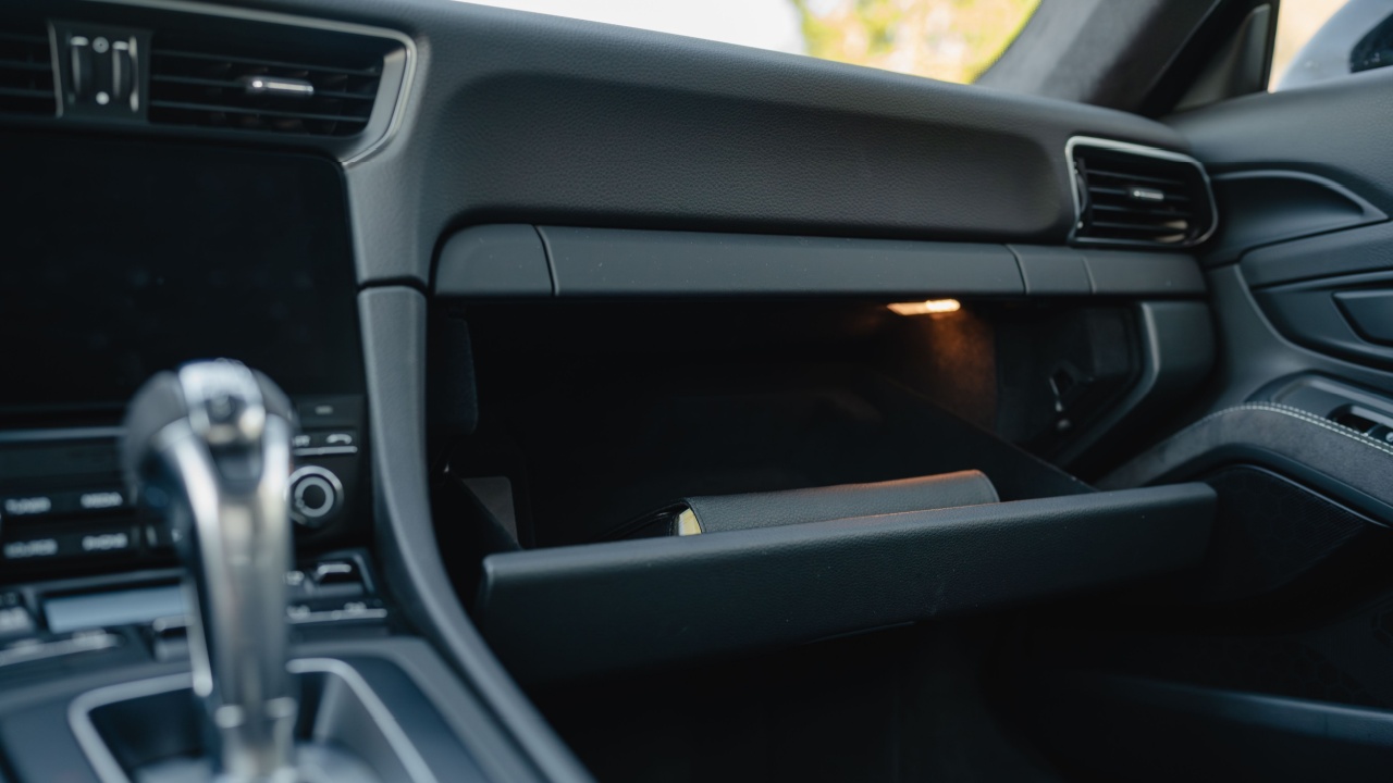 Minimalist glove box design with smooth, black interior finish in a luxury vehicle.