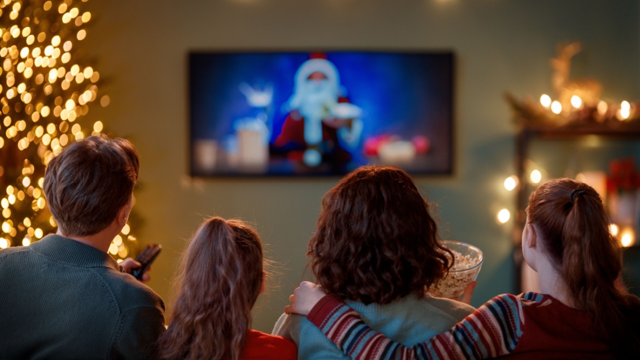 Merry Christmas and Happy New Year. People having fun near tree indoors. Loving family watching holiday movies at home. Mother, father and daughters spending time together.