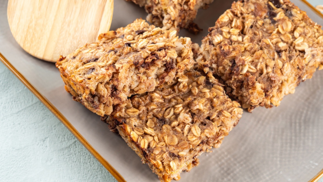 Vegan oatmeal banana cake bars on gray dish. Healthy breakfast baked porridge bars with rolled oats, banana, peanut butter, soy milk and chocolate chips