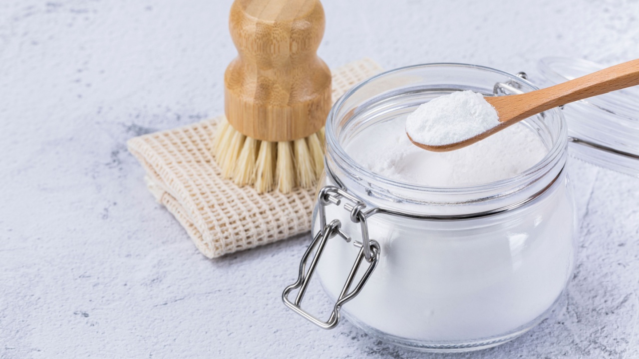 Zero waste - glass bottles and wooden spoon containing bamboo and natural sponges, cleaning brush and baking soda