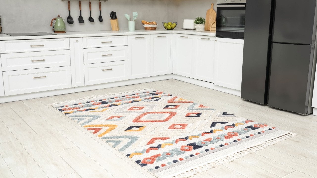 Stylish soft rug on wooden floor in kitchen