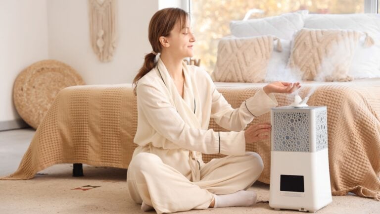 Young woman turning on air humidifier on carpet in bedroom