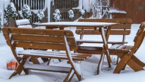 snow-covered garden lounge set not hidden and not protected for the winter. snow on benches, table and wooden chairs. harsh winter