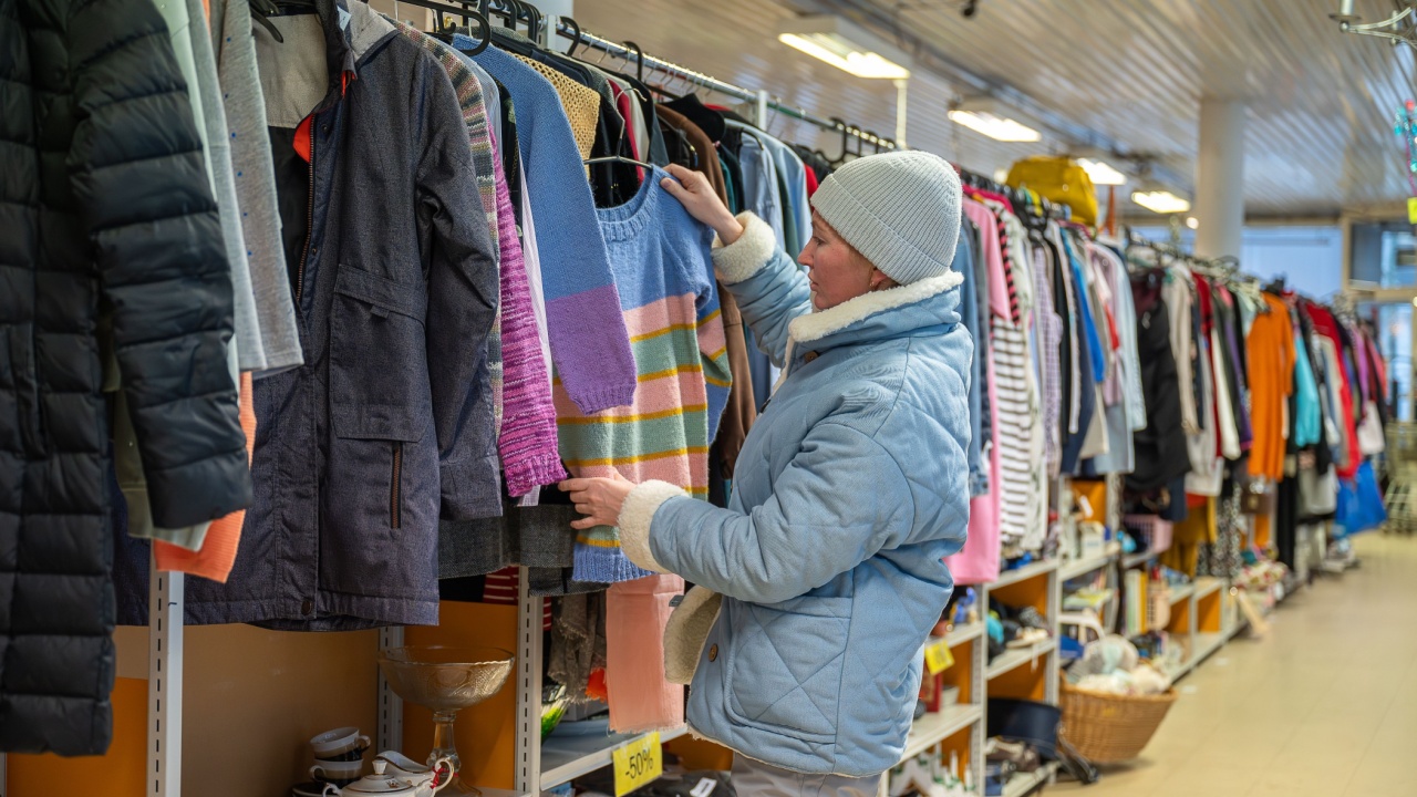 Woman browsing clothes in a thrift shop. Second hand concept