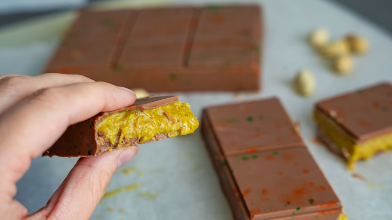 Piece of trend Dubai chocolate with pistachio paste and kataifi dough in woman hand. Confectionery handmade sweets at home in the kitchen. . High quality photo