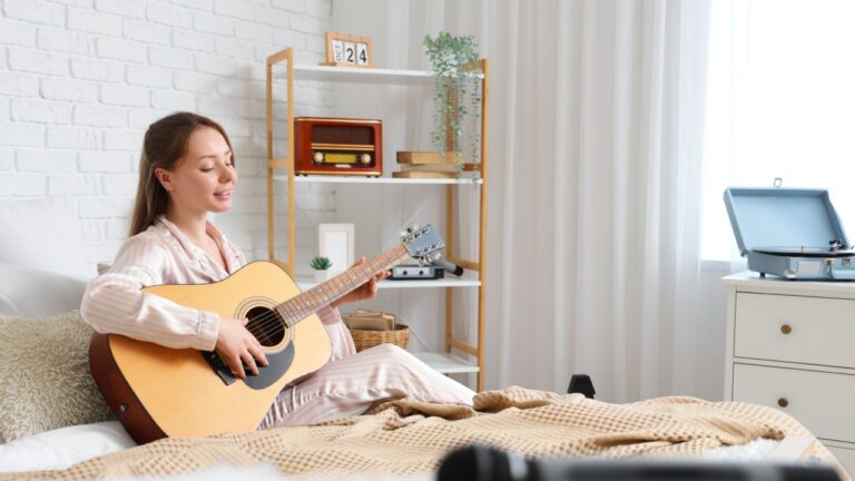 Young woman playing guitar in bedroom