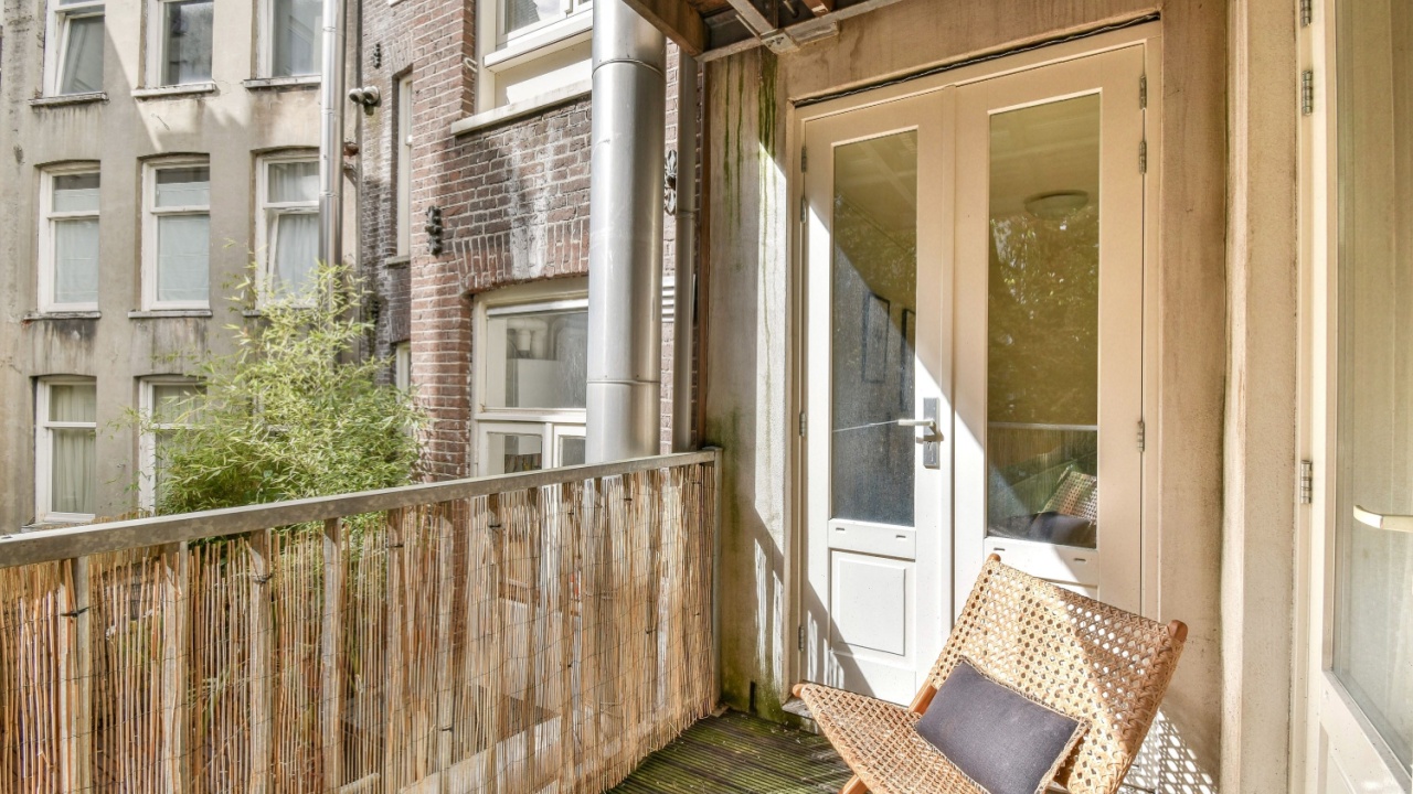 A tranquil balcony space featuring a chair and decorative elements, surrounded by greenery and urban architecture, perfect for relaxation and fresh air.