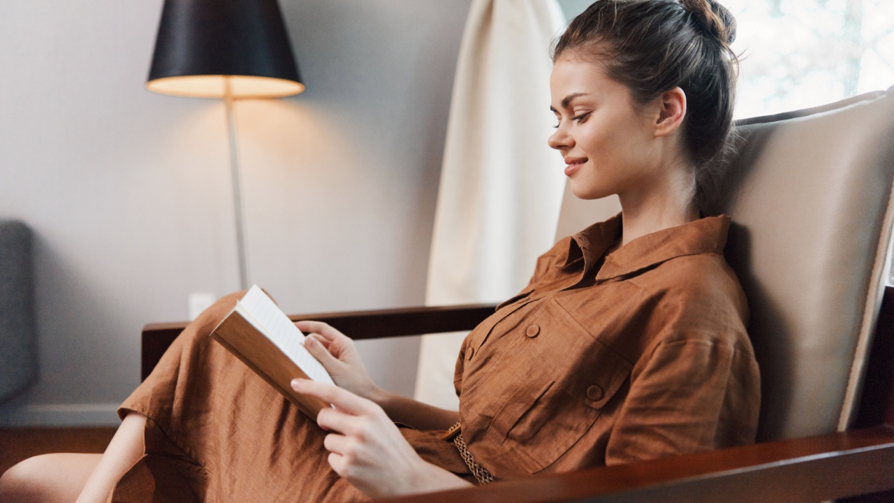 A serene young woman reading a book in a cozy, stylish living room featuring warm tones and soft lighting for a relaxed atmosphere