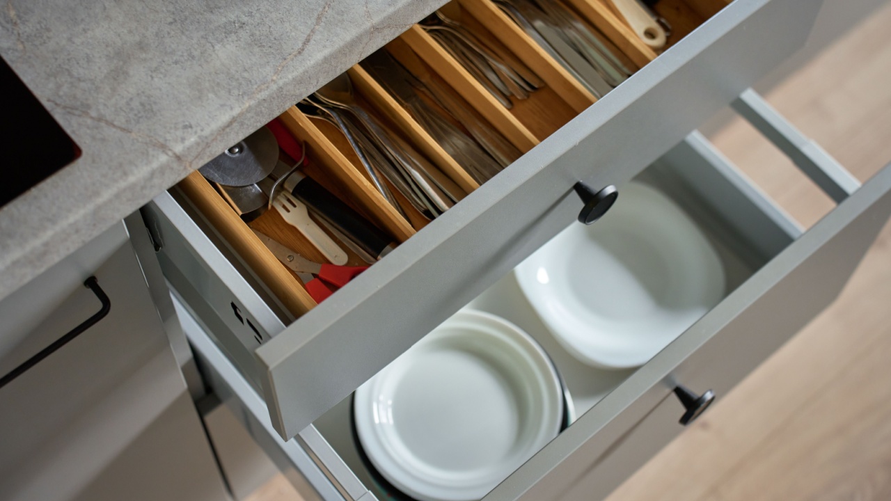 Modern kitchen with dishes and cutlery in open drawers. Contemporary kitchen cabinets. Concept of home organization and functionality interior