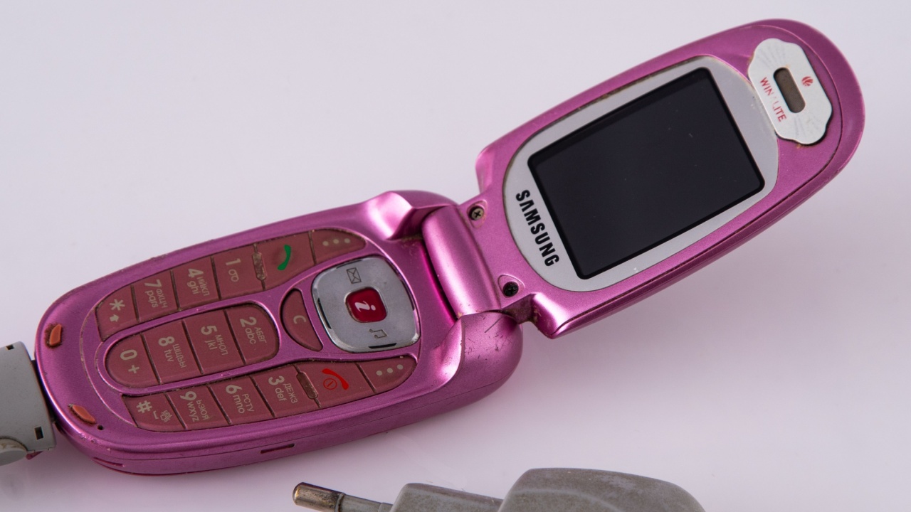 Old Samsung push-button flip phone. Pink color display with charger. Retro mobile telephone. Ukraine, Kyiv - January 25, 2025