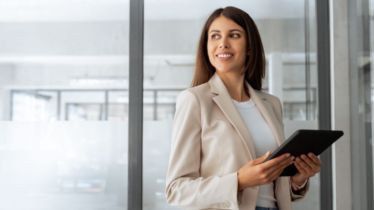 Young smiling latin hispanic woman using computer for business working application. Businesswoman professional boss holding digital tablet pc device for work in office, looking dreaming at copy space