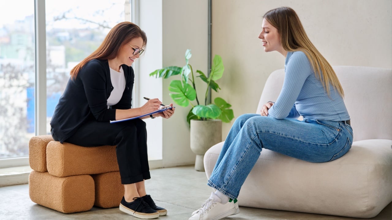 Young smiling woman in mental therapy talking with professional psychologist
