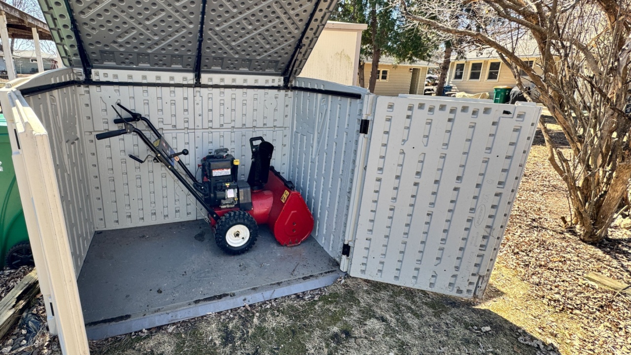 New Hope, Minnesota - April 5, 2025: Outdoor shed with all of its doors and roof open, with a snow blower inside