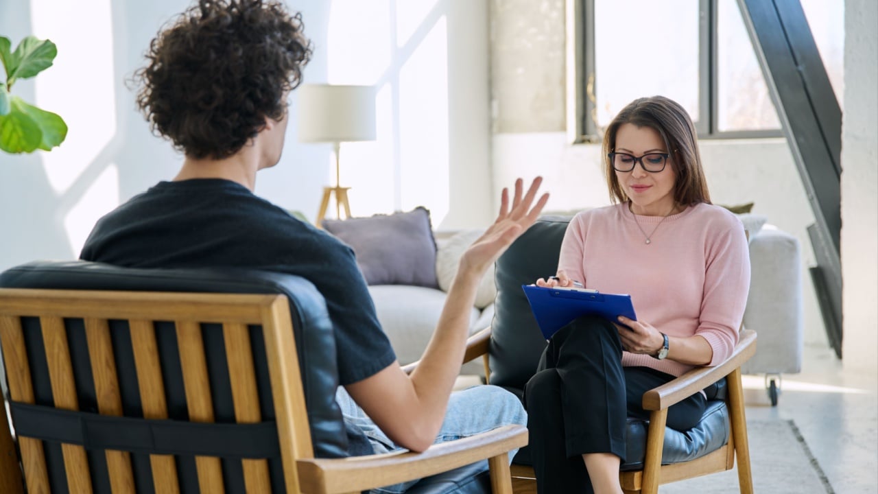 Middle aged female professional mental therapist working with young male patient