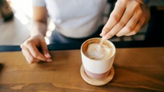 Close up of woman stirring coffee in coffee shop.