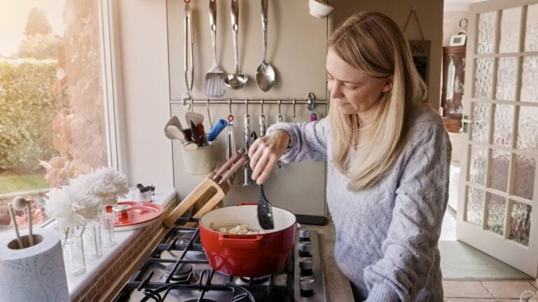 Woman, cooking and pot stove in kitchen for warm food, stew dinner or vegetable hunger. Female person, gas appliance and prepare nutrition eating as soup diet for fresh taste, hobby dish or healthy