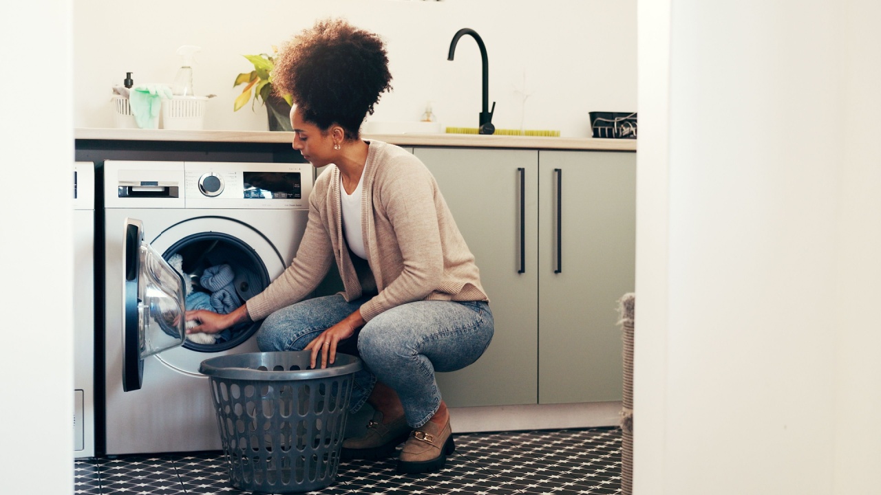 Clothes, basket and laundry with woman and washing machine for cleaning, hygiene and fabric softener. Housekeeping, loading and chores with person in home for washroom, fresh linen and detergent