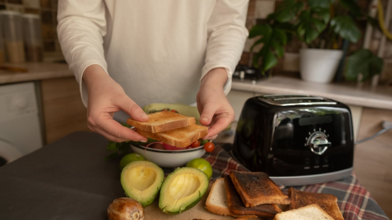 Woman in kitchen with toaster morning preparation of healthy food at home simple routine for nutritious breakfast.