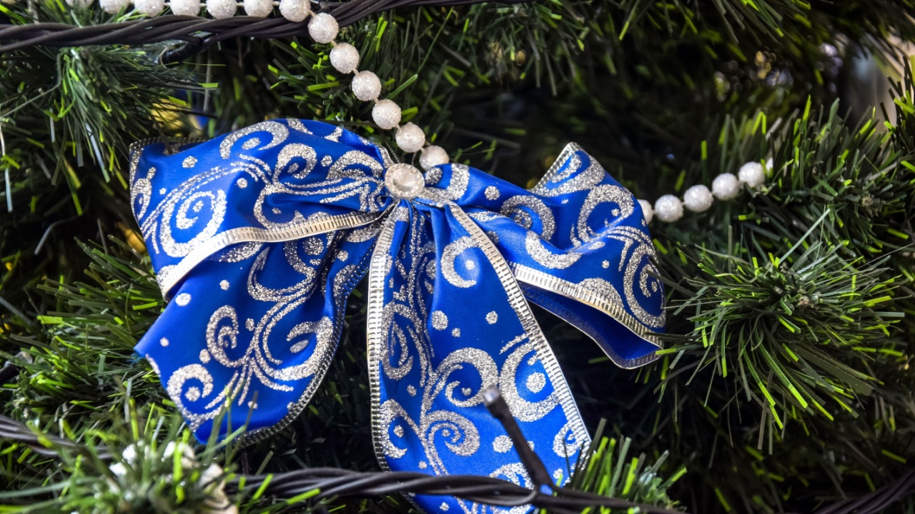 Vintage Christmas bow made of blue ribbon on artificial Christmas tree. Ornaments for the New Year, old-fashioned decoration. Close-up