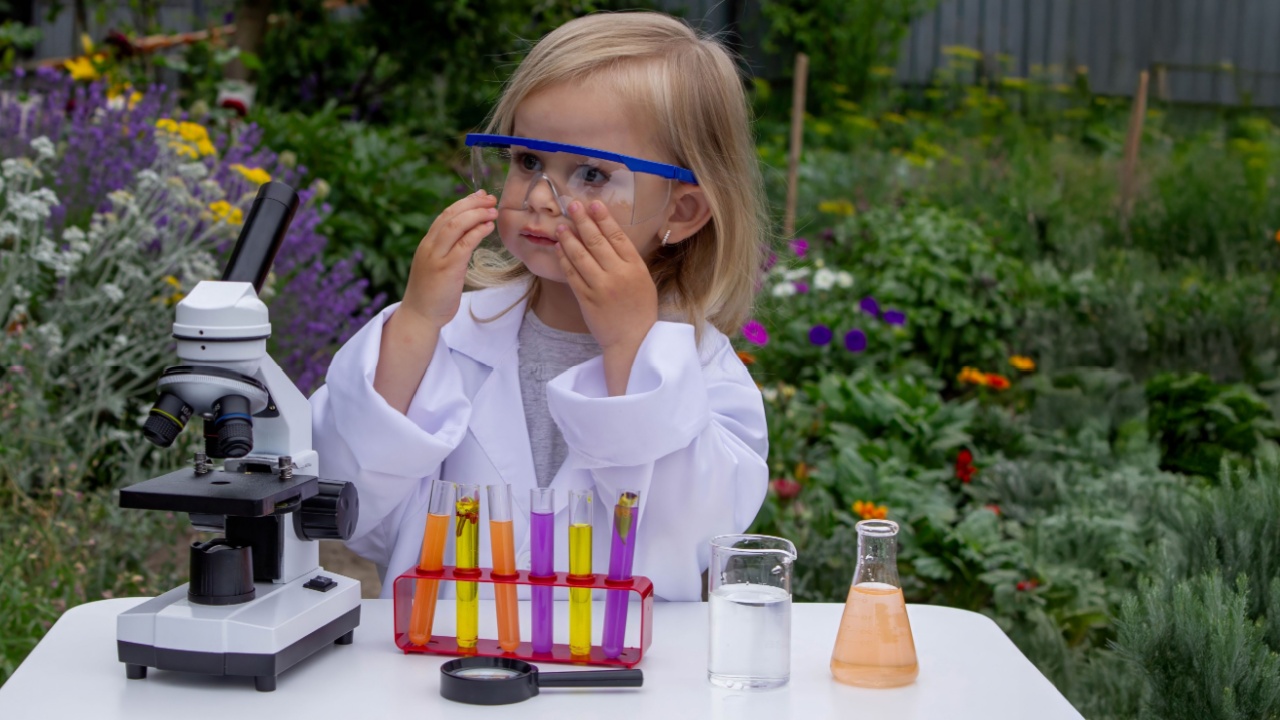 A little girl conducts experiments using test tubes, reagents, and a microscope