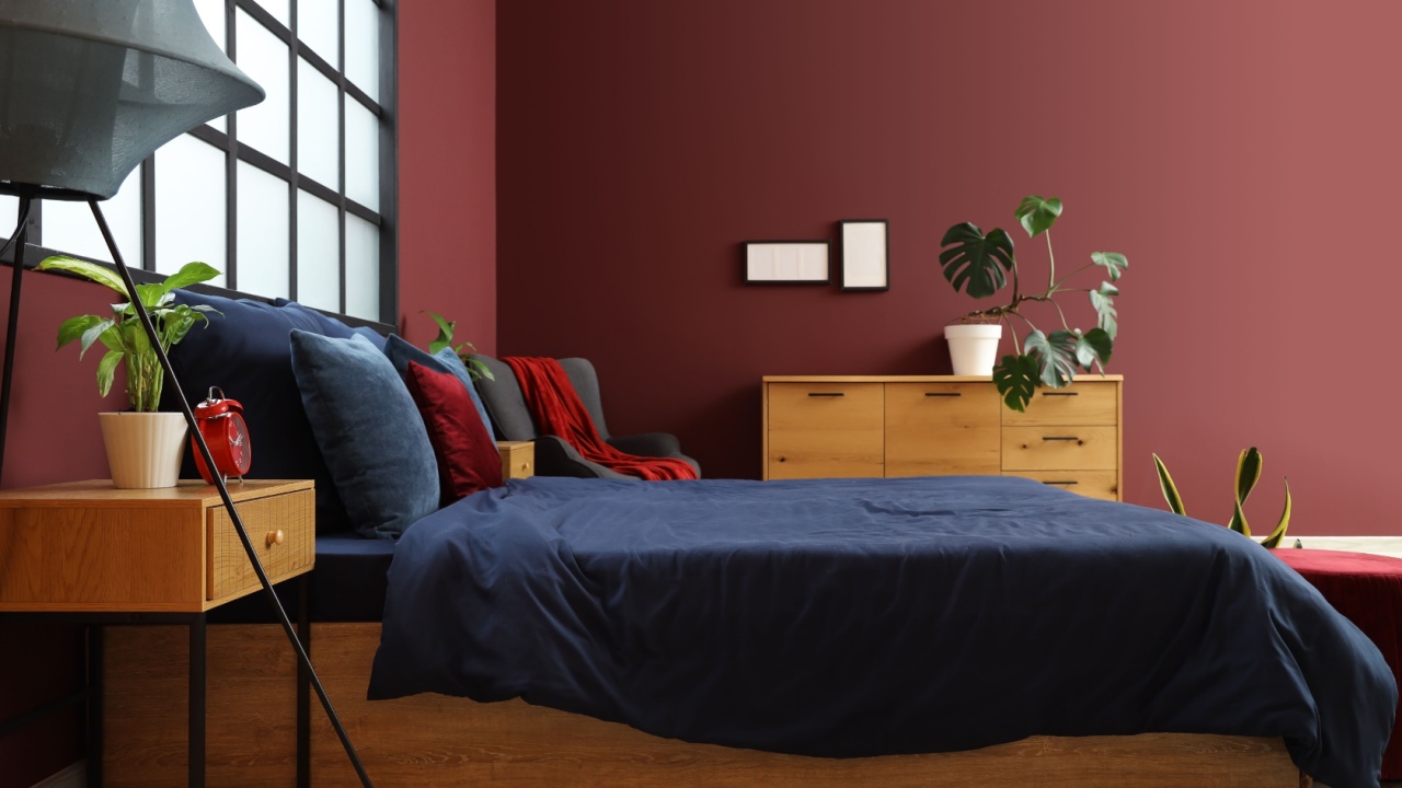 Interior of stylish bedroom with navy blue linen, armchair and plants