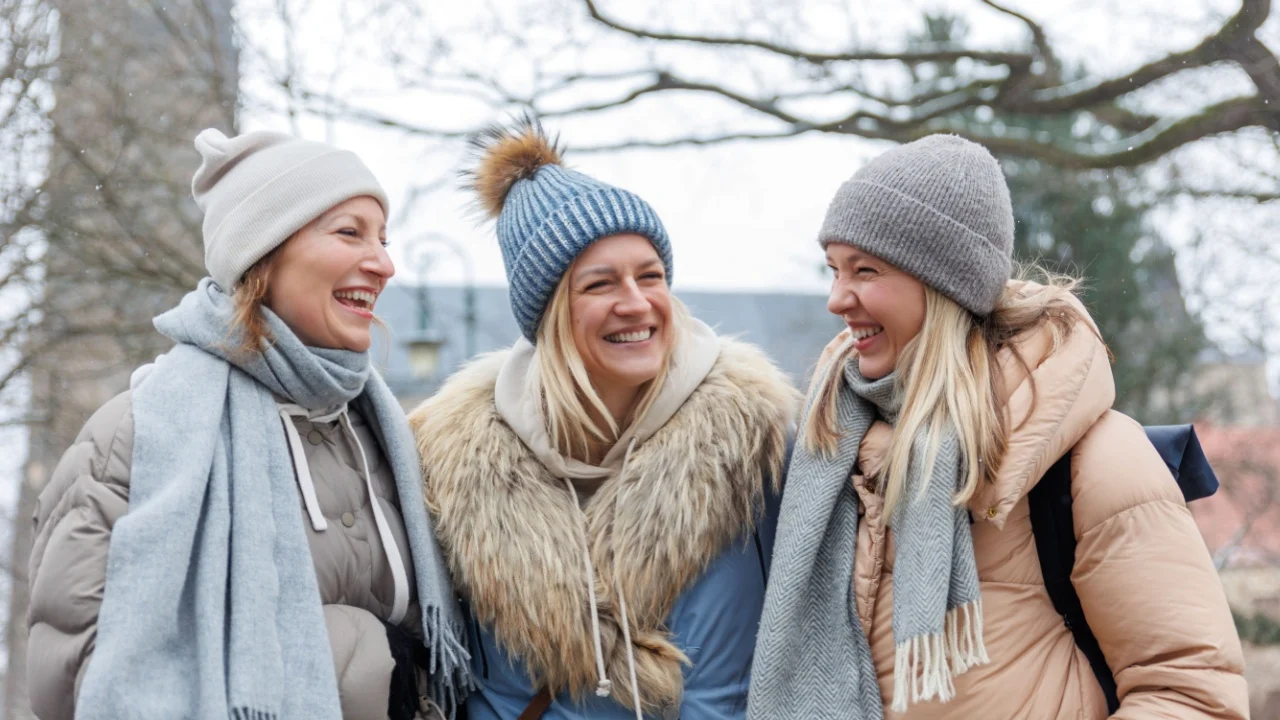 Three cheerful young adult women friend walk Magdeburg street old european uk german town city street enjoy having fun laughing cold winter day together. Female persons friendship celebration weekend.