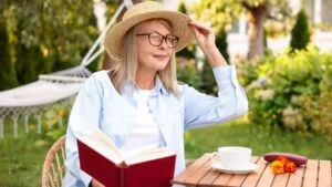 Senior woman reading book at wooden table in garden