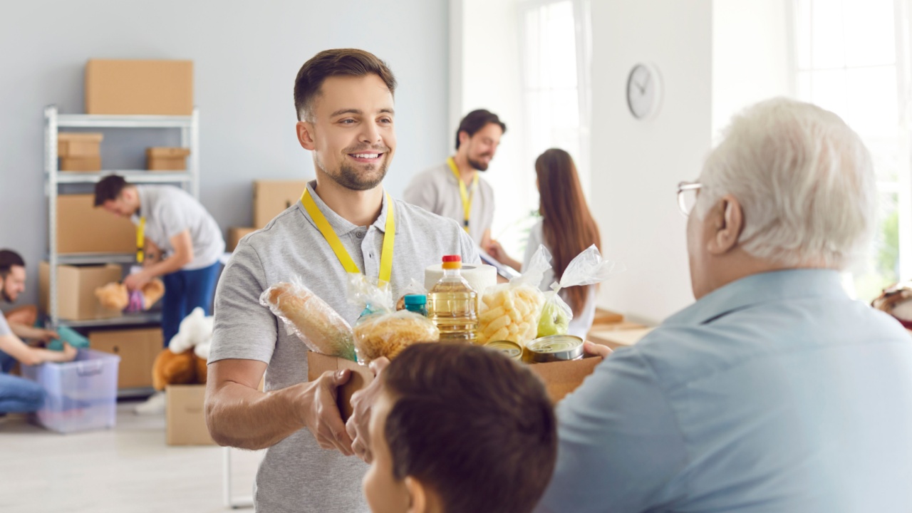 Volunteering people, food bank box giving help to old senior man, male volunteer working in charitable meal foundation making donation, charity separating basic need provisions, free meal help care