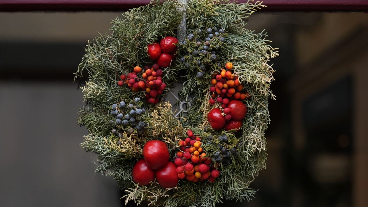A Christmas wreath of red berries and apples hanging on a door