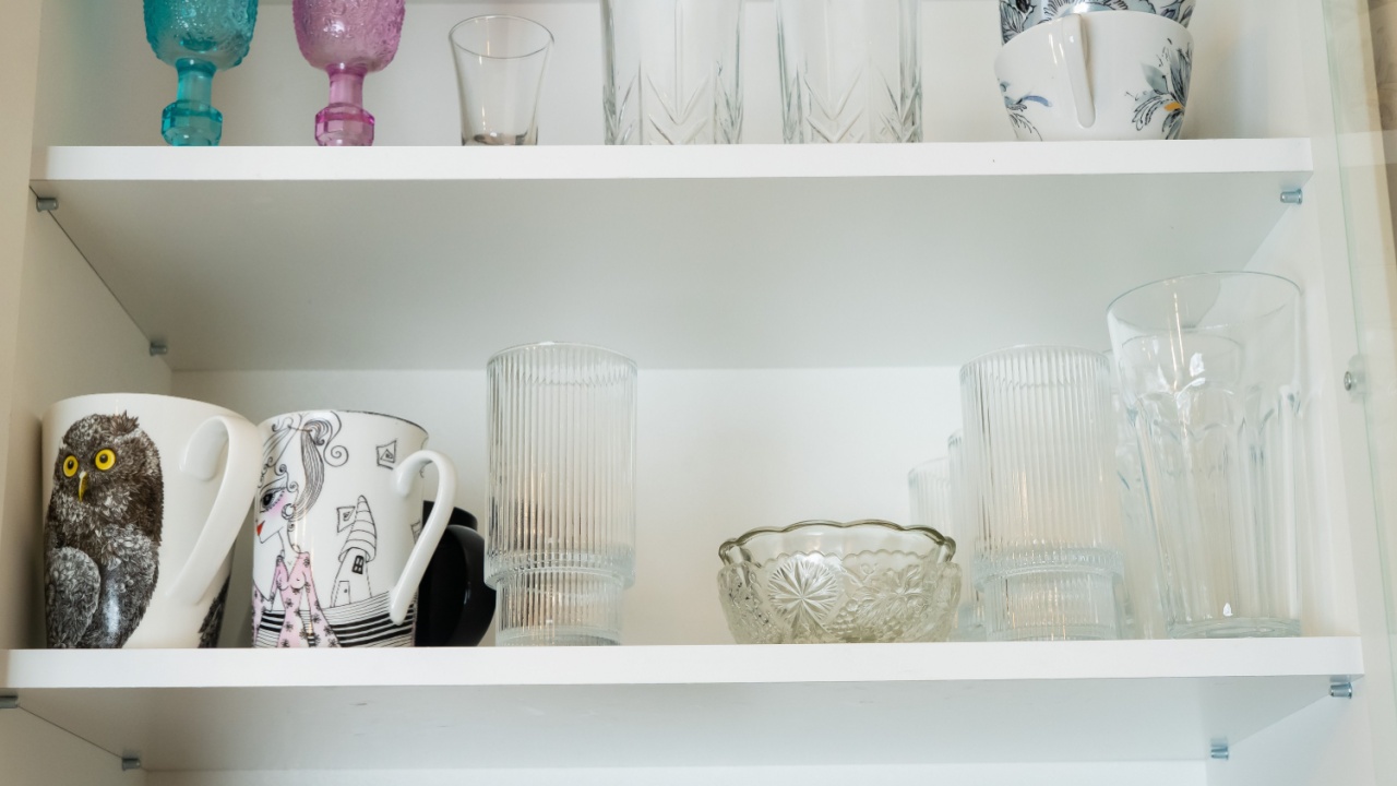 Shelf with assorted glassware and mugs, creating a bright, organized kitchen cupboard scene.