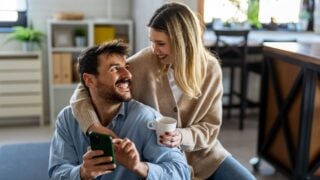 Happy couple using smartphone for social media mobile banking and modern digital lifestyle together