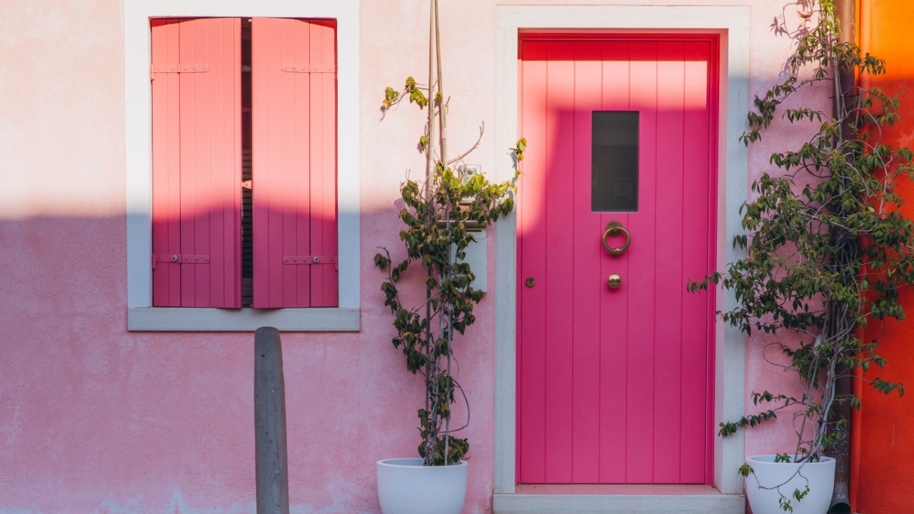Burano Island house featuring a vibrant pink door and matching shutters, reflecting the colorful architecture of the Venetian lagoon