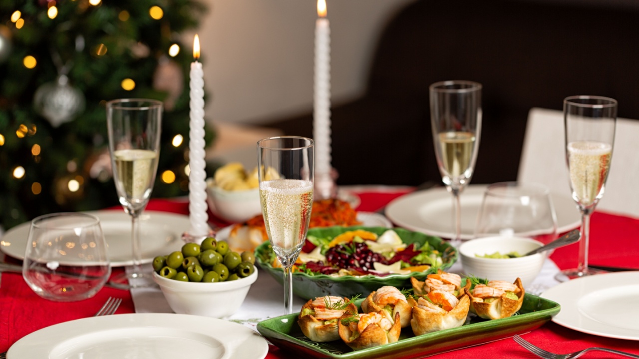 Served Christmas, New Year table with homemade food, canape, prawn and guacamole tartlets, winter salad, olives, glasses with white wine. Home interior with Christmas tree on background. Dinner.