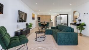 Torrevieja Spain 24 September 2025: Stylish open-plan interior with green velvet furniture, wooden kitchen, and cozy lighting accents.