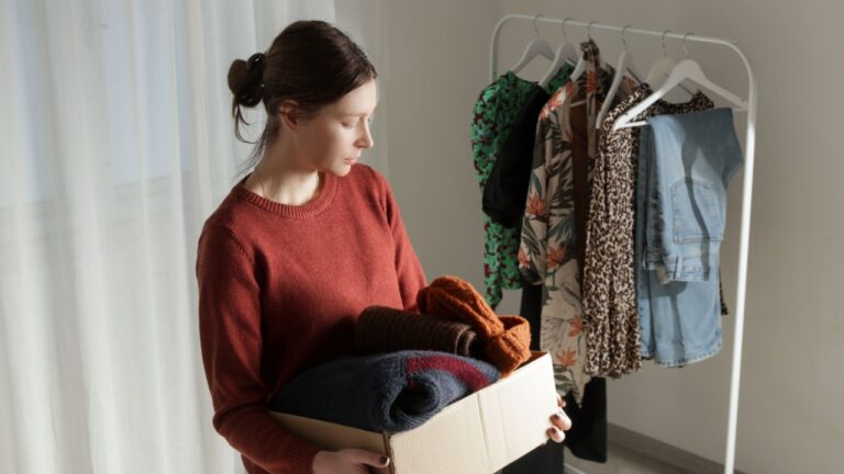 Woman Sorting and Packing Clothes into Cardboard Box at Home