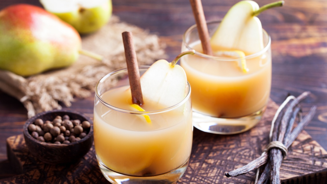 Pear mulled cider with vanilla,lemon slice and cinnamon sticks on a wooden background
