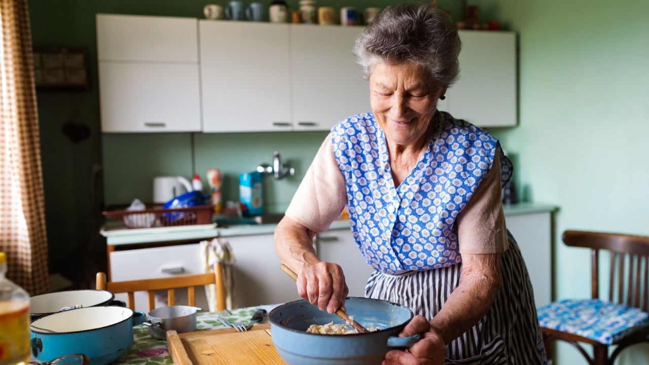 Senior woman baking pies in her home kitchen. Mixing ingredients.